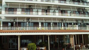 A multi-story hotel with outdoor seating and potted plants. - Hotel Poseidon (Chalcis)