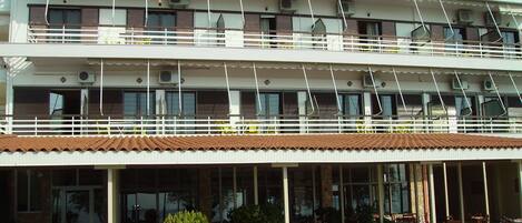 A multi-story hotel with outdoor seating and potted plants.