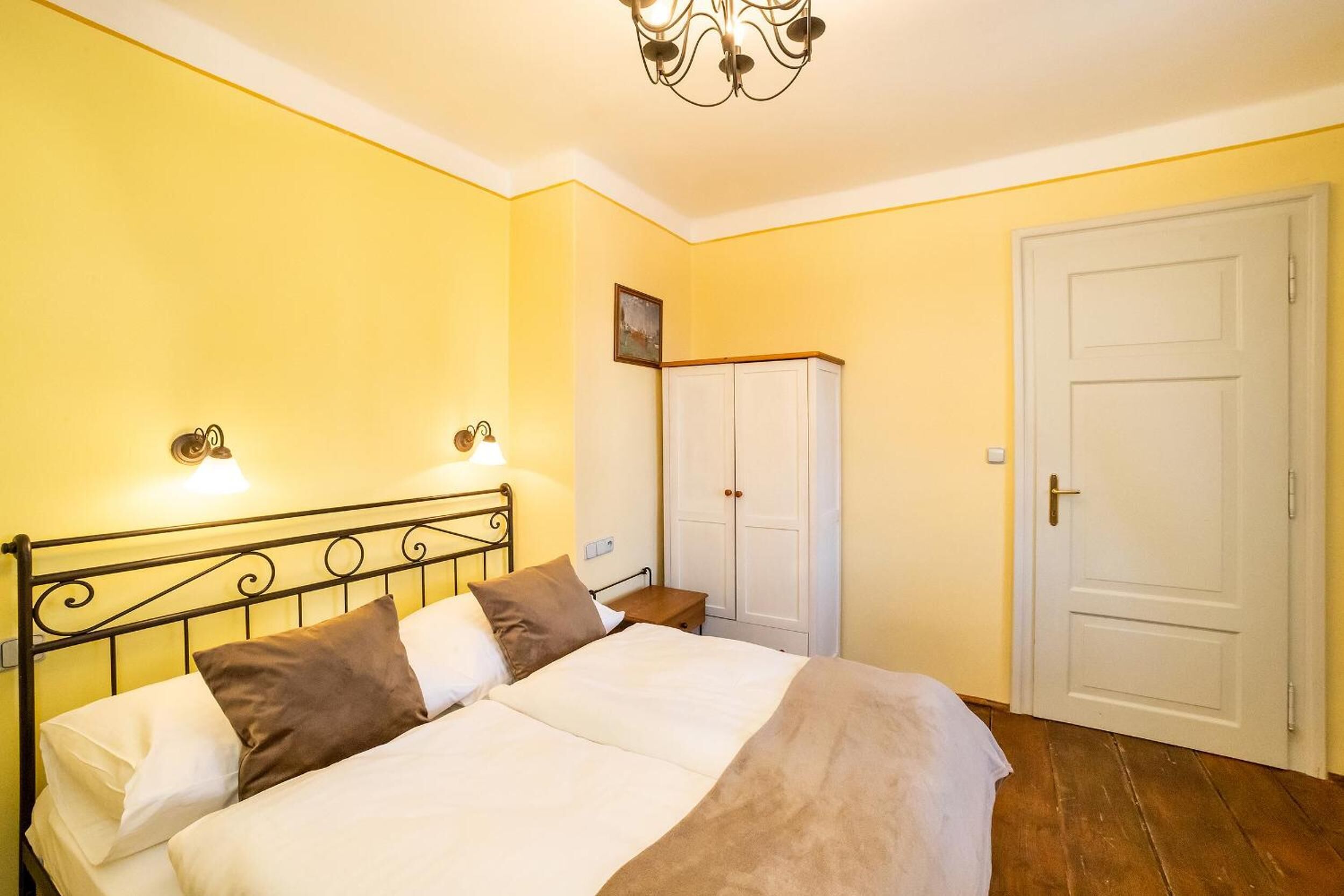 Un dormitorio con cama, lámparas de noche, armario y una puerta.