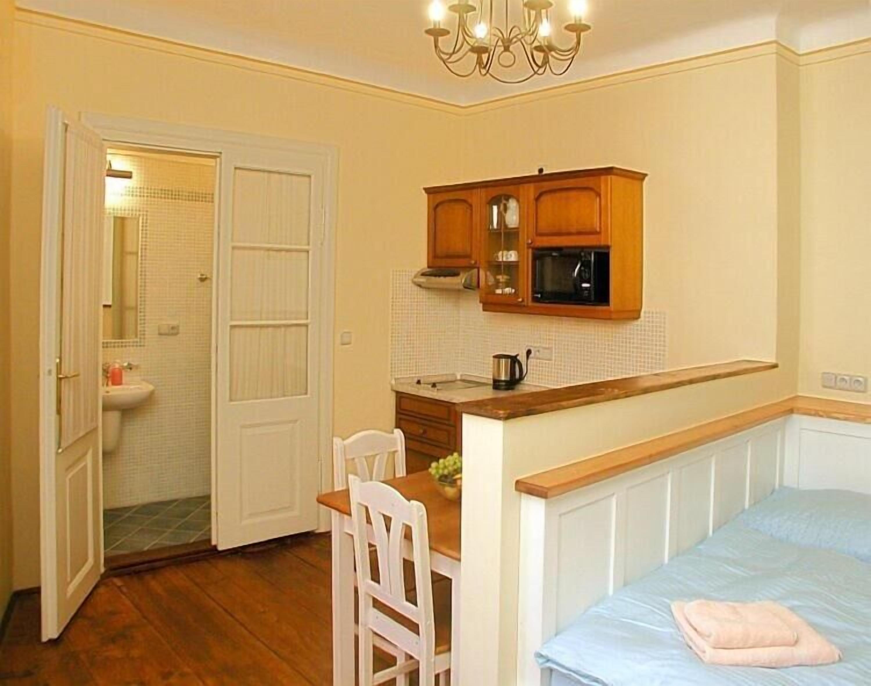 Een knus slaapkamer met een enkel bed, een klein tafeltje en een stoel. Grenzend is een kitchenette met een magnetron en een koffiezetapparaat.