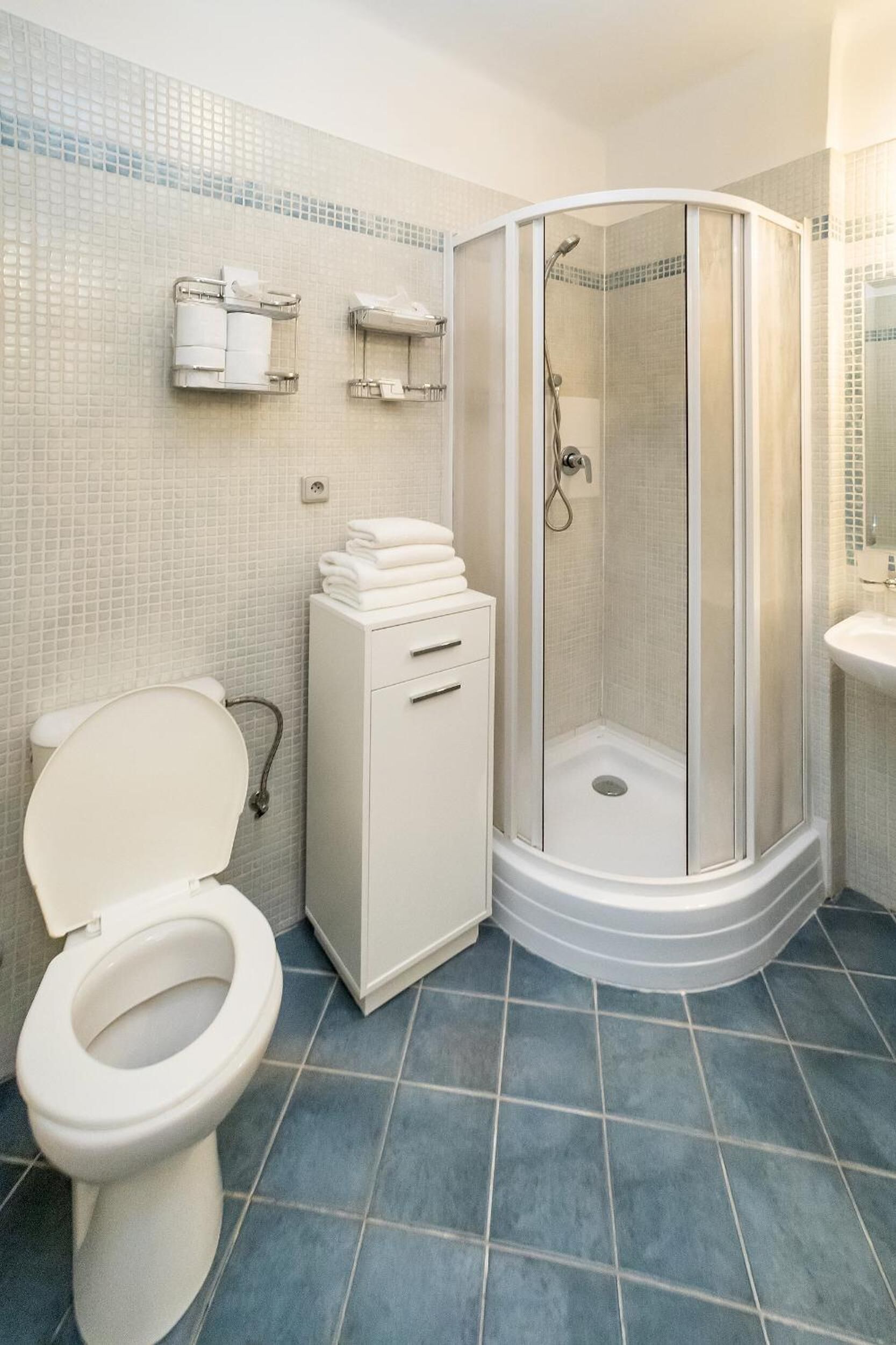 A bathroom with a toilet, a shower enclosure, and a sink.