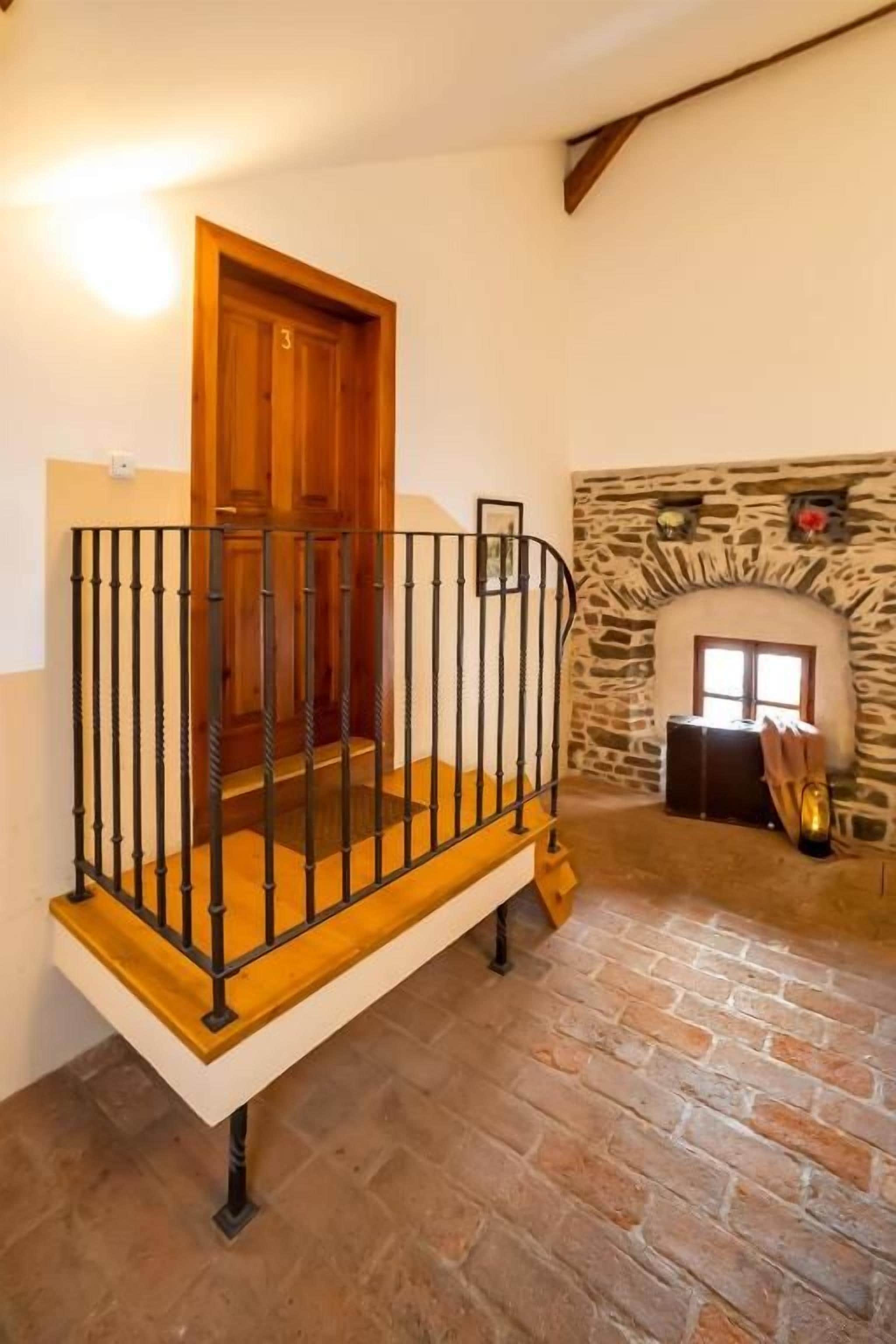 Una escalera con barandilla de madera y balaustres negros, que lleva a una puerta de madera.