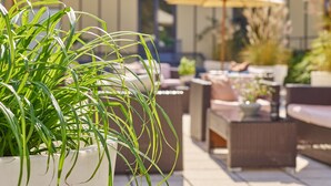 A patio area with outdoor furniture and a potted plant. - DAS LUDWIG Sports Resort (Bad Griesbach im Rottal)