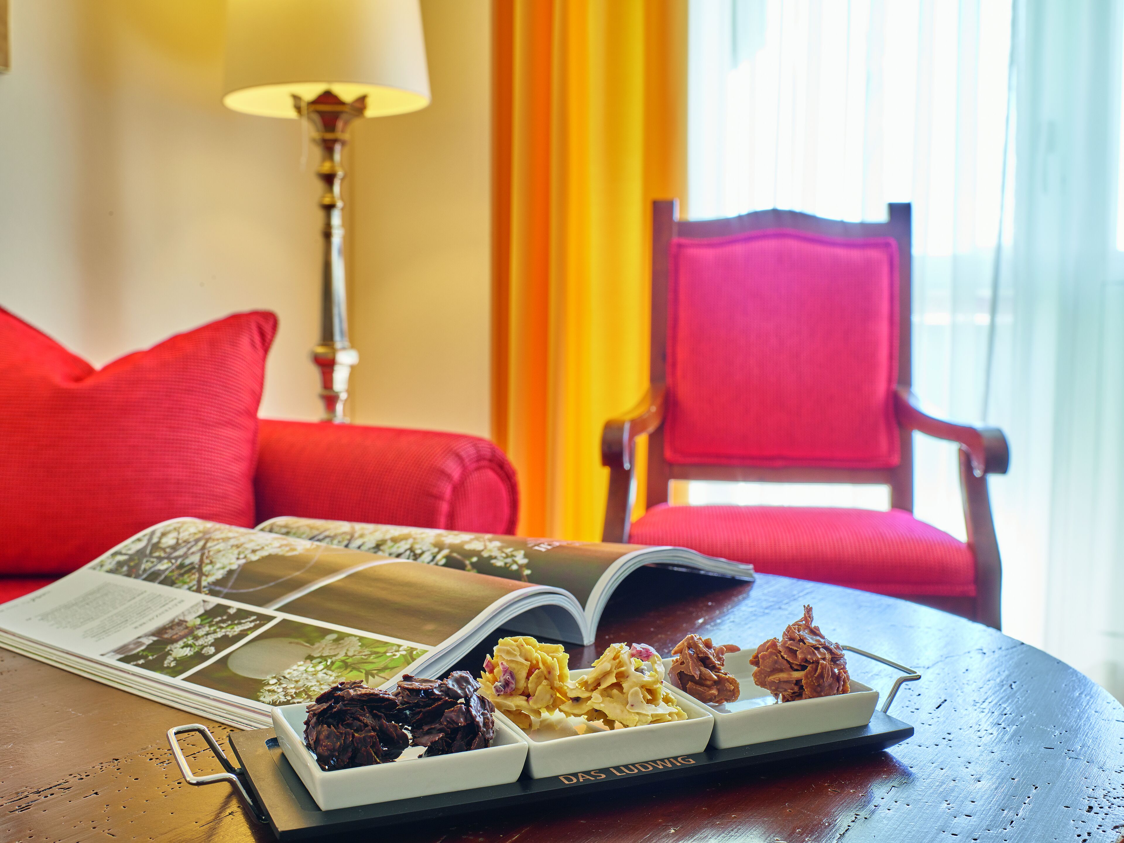 A dining table with a book, a pair of scissors, and three plates of food.