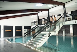 Una piscina con barandilla de vidrio y una escalera que sube a un nivel superior.