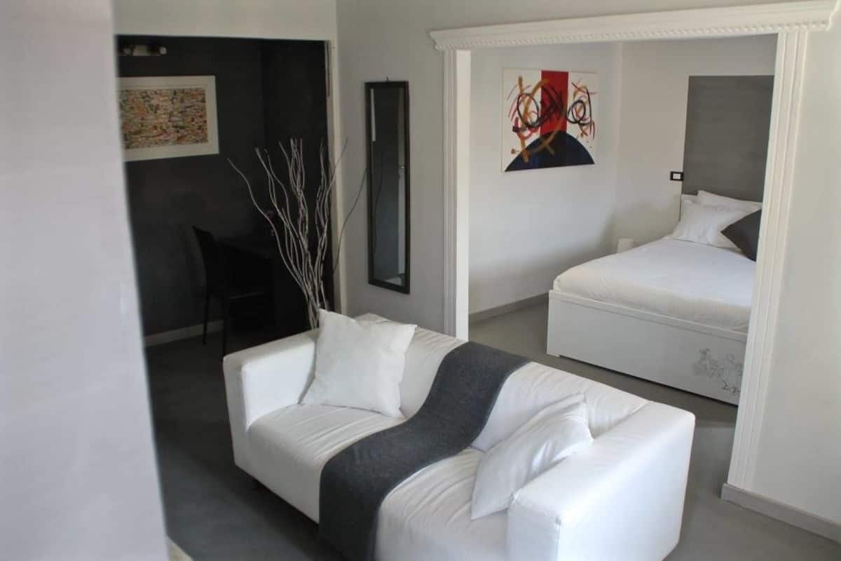 Ein modernes Hotelzimmer mit einem weißen Sofa, einem Bett und einem Schreibtisch.