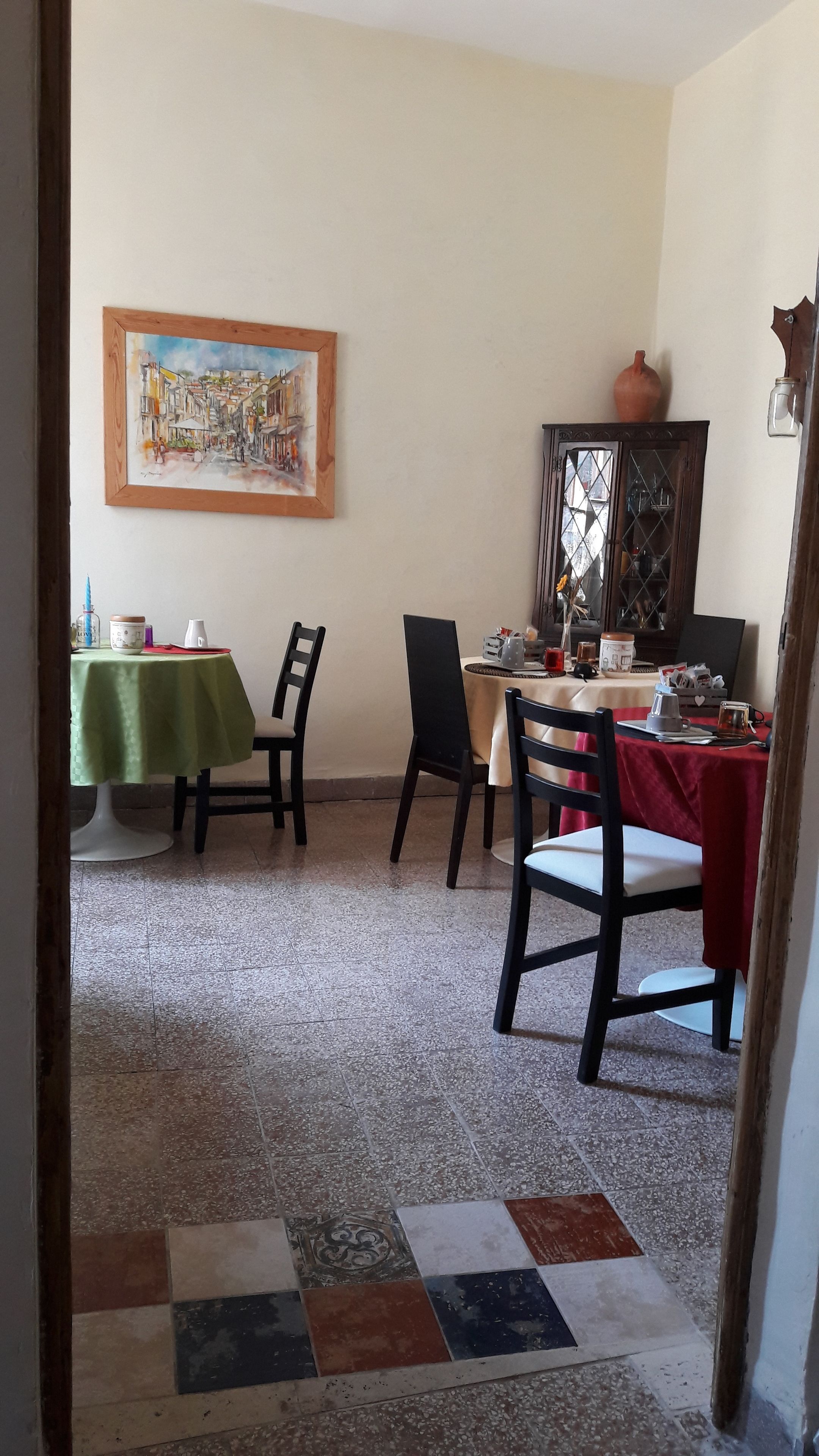 Un'area pranzo con un tavolo verde, un tavolo rosso e un quadro appeso al muro.