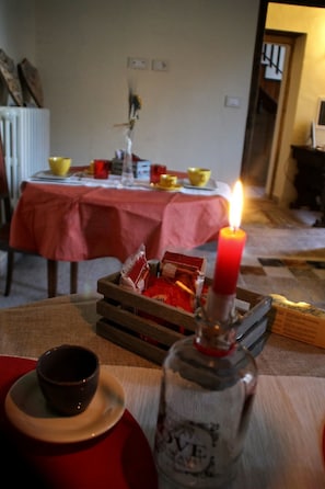 Una mesa para comer con una vela, una botella y una taza.