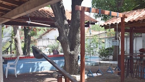 An outdoor patio area with a swing set, a blue and white wall, and a tree. - Pousada Chalé Suiço (Parnaíba)