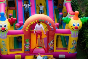 Uma estrutura inflável colorida com escorregadores e um arco com tema de palhaço.
