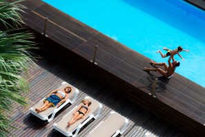 Un espace aménagé au bord de la piscine, avec des chaises longues et une terrasse en bois.