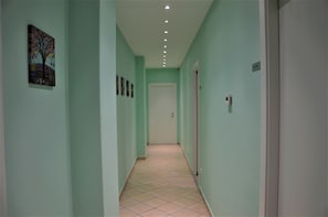 Un passadís amb parets verd clar, un sòl de rajola i una porta al final.