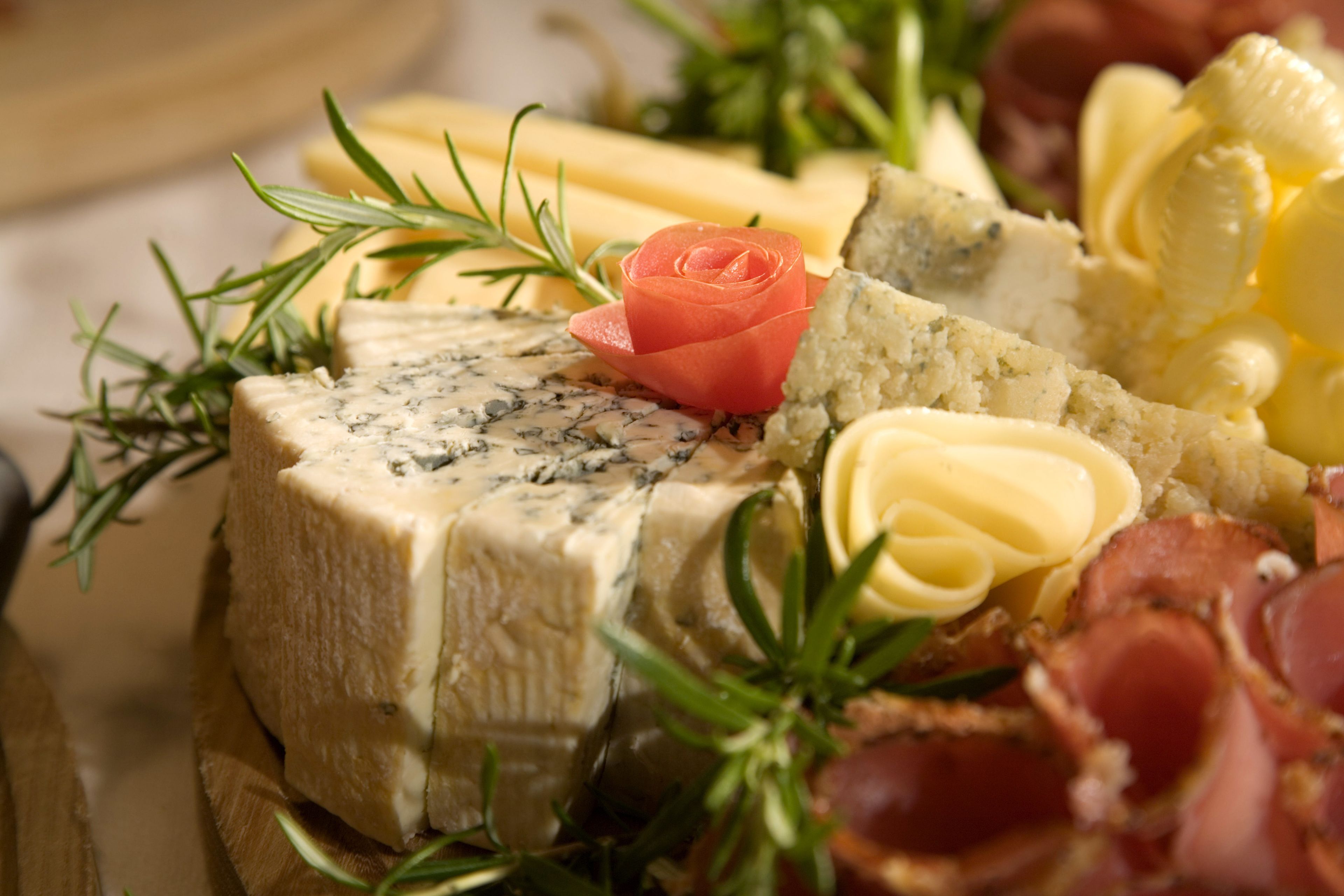 Tagliere con diversi formaggi, salumi e guarnizioni.