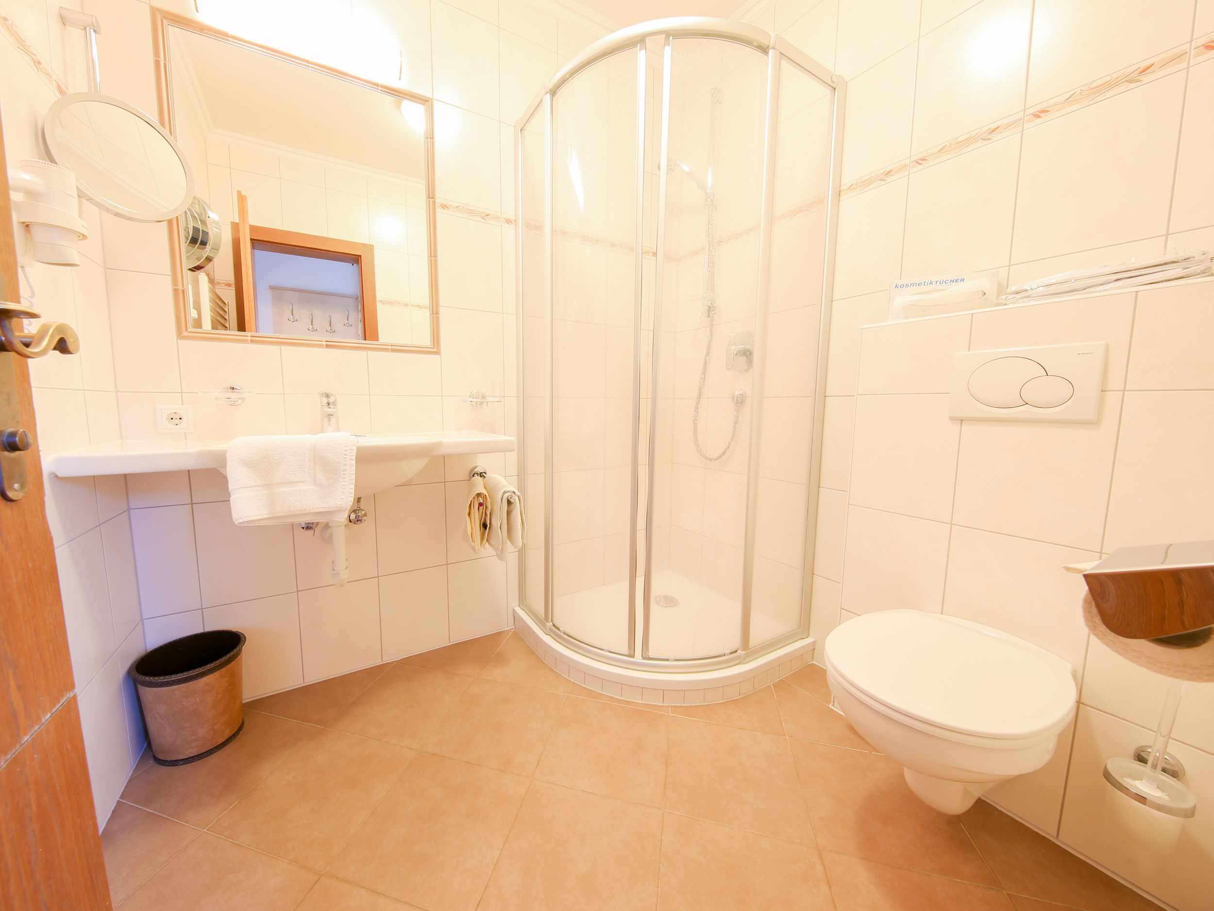 Un bagno con cabina doccia in vetro, un lavandino bianco e un water.