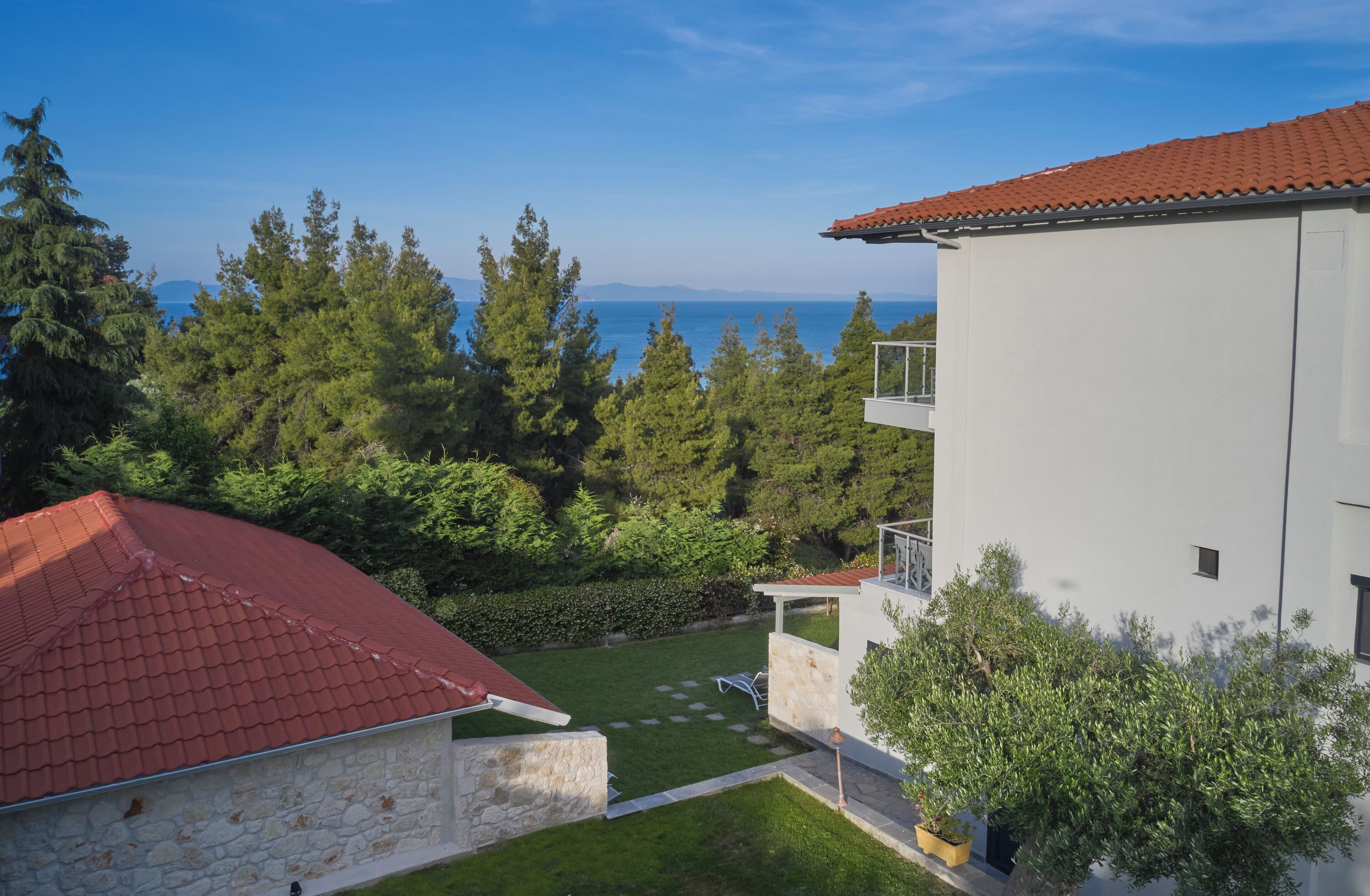 A modern building with a red-tiled roof, a stone wall, and a well-maintained lawn.