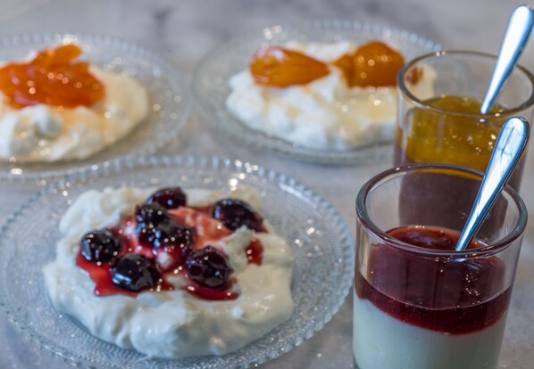 Tres platos de postre con crema batida y frutas, además de un vaso de gelatina y una cuchara.