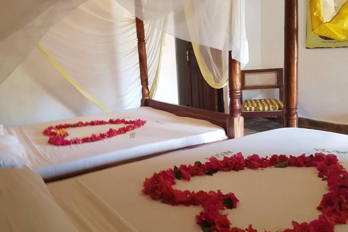 Une chambre d’hôtel avec deux lits, chacun décoré d’un arrangement de fleurs rouges en forme de cœur.