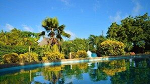 A swimming pool surrounded by lush greenery and palm trees. - Kenga Giama Resort (Malindi)