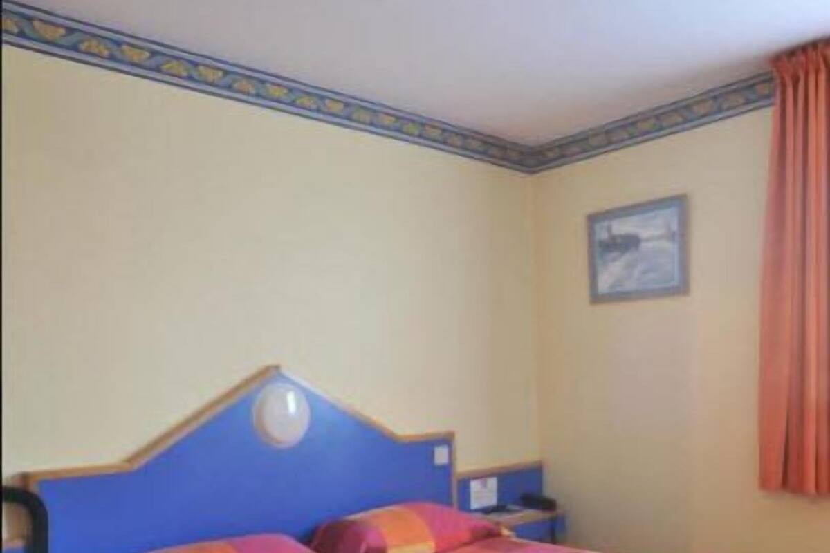 Ein Zimmer mit zwei Betten, einem Nachttisch und einer Wandlampe.