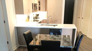 Moderni keittiö, jossa on keskeinen keittiösaareke, tumma puulattia ja integroidut kodinkoneet.