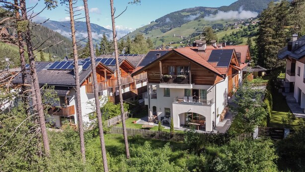 Una moderna cabaña con techo inclinado, paneles solares y vistas de las montañas circundantes.