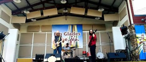 A stage with a band performing under a metal roof structure.