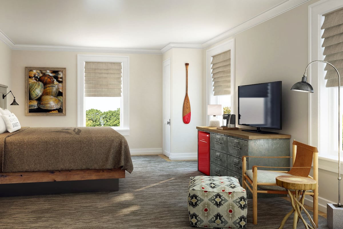 A bedroom with a bed, bedside table, lamp, artwork, TV, and a desk with a chair.