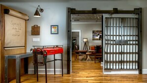 A room with a wooden floor, a red vintage car, a metal table, a lamp, and a sliding door with a metal grid. - Western Front Hotel (St. Paul)