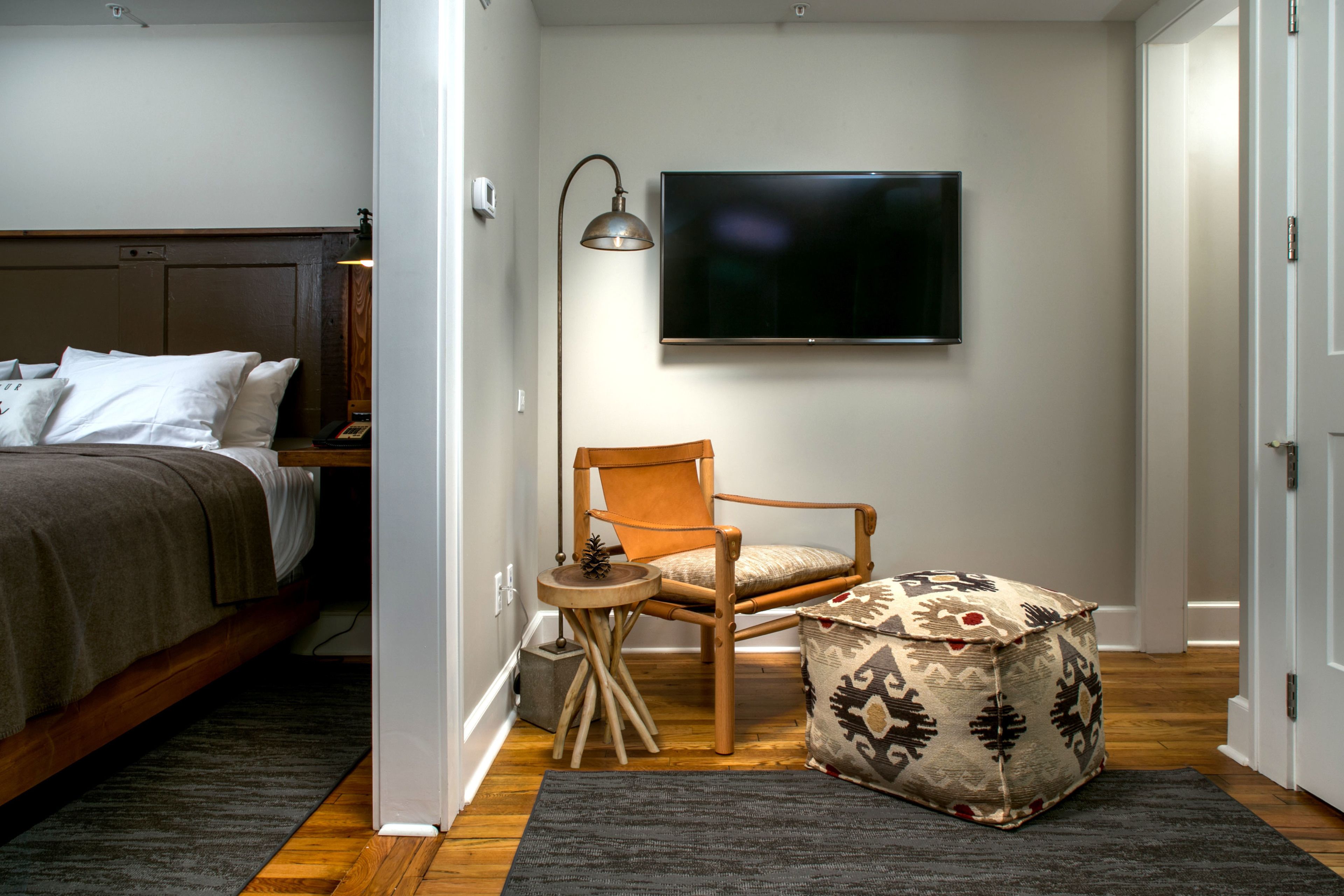 A bedroom with a bed, a chair, a TV, and a small table.