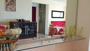 Une cuisine moderne avec une cloison en verre, des tabourets de bar rouges et un coin repas agrémenté d’une chaise rembourrée de couleur rouge.