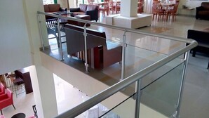 Un hall d’hôtel spacieux, doté d’une rambarde en verre, de plusieurs espaces aménagés pour s’asseoir et offrant une vue sur la terrasse extérieure.