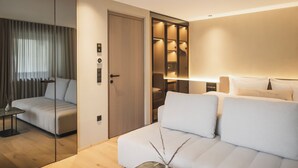Ein modernes Hotelzimmer mit Bett, Sitzecke und begehbarem Kleiderschrank.