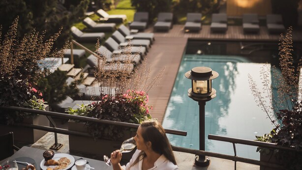 Ein Essbereich am Pool mit Liegestühlen, einem Pool und Blick auf den umliegenden Wald.