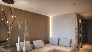 Ein modernes Wohnzimmer mit einem Ecksofa, zwei weißen Vasen mit Pflanzen und einer außergewöhnlichen Deckenleuchte.