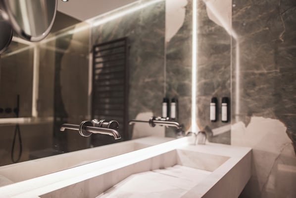Un baño moderno con un espejo grande, un lavamanos rectangular y una zona de ducha.