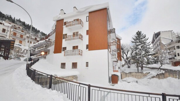A multi-story building with balconies, a snow-covered street, and a metal fence. - Amami Viaggi - Casa del Sannio (Roccaraso)