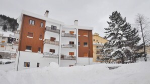 A multi-story residential building with balconies and a snow-covered ground. - Amami Viaggi - Casa del Sannio (Roccaraso)
