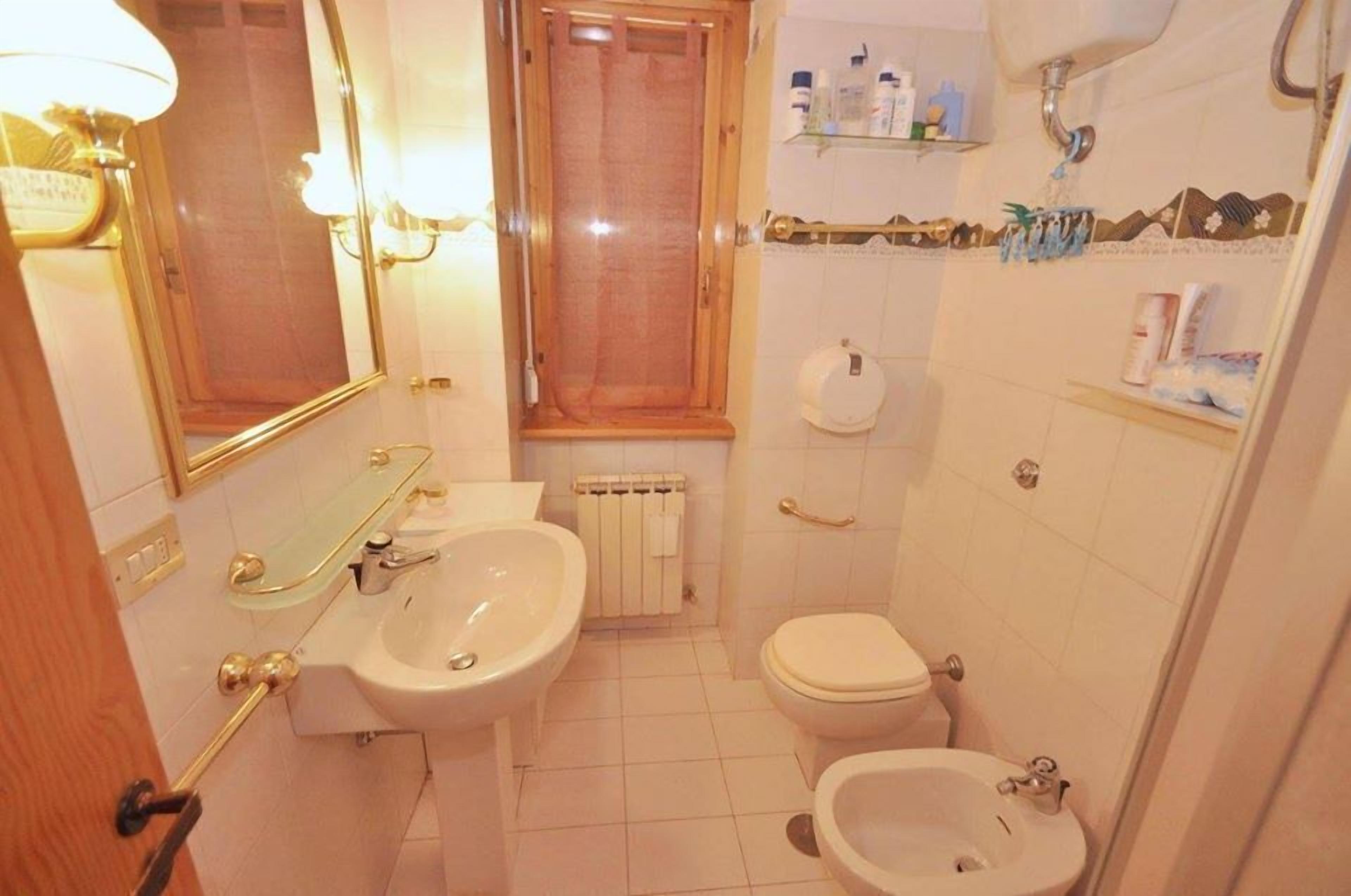 A bathroom with a sink, toilet, bidet, and a mirror.