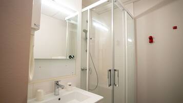 Un baño moderno con cabina de ducha de vidrio, un lavabo blanco y un espejo sobre él.