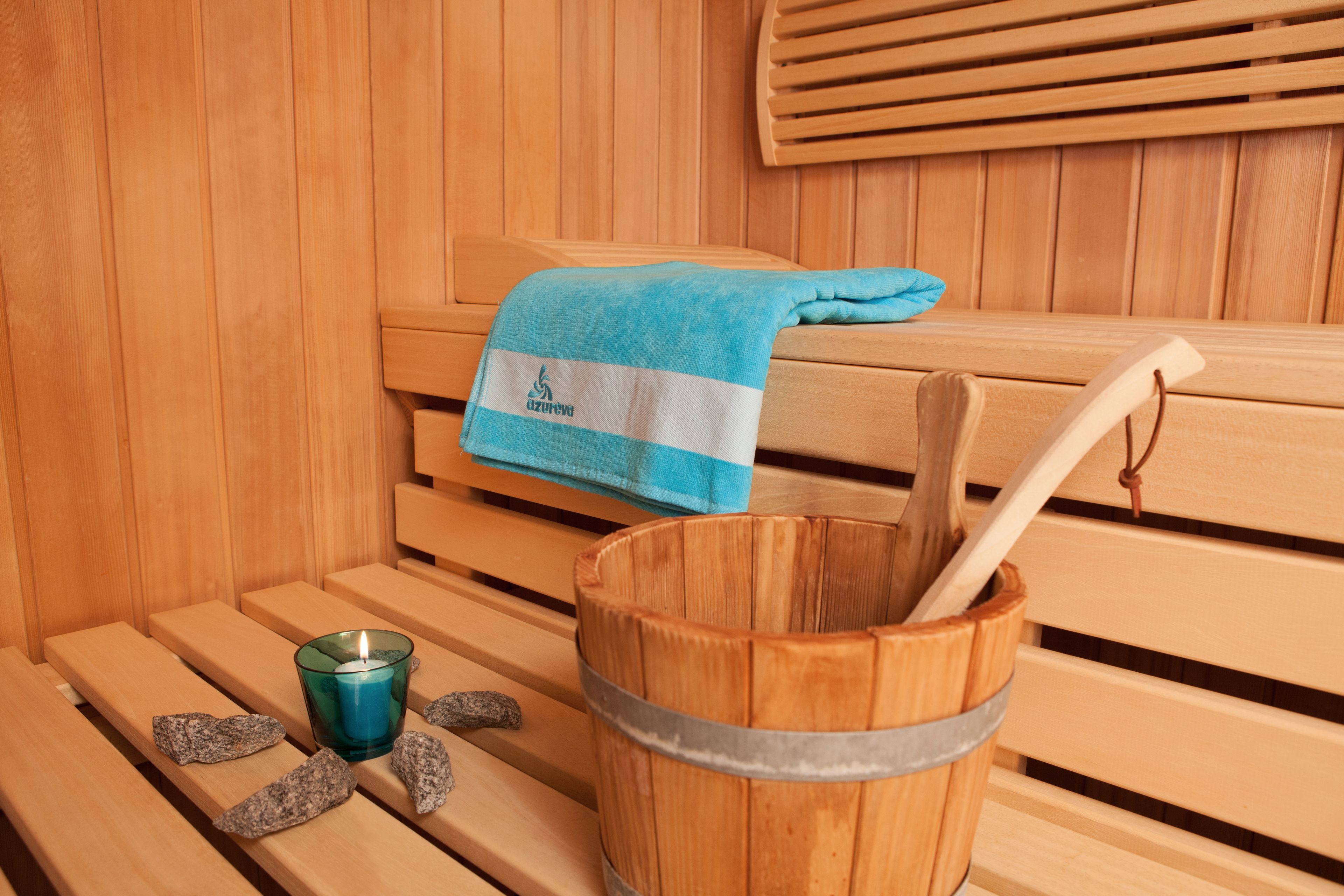 A wooden bench with a towel and a bucket with a wooden mallet.