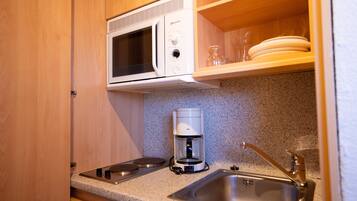 A compact kitchen with a microwave, coffee maker, and a sink.