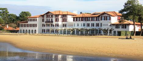 A large hotel with multiple floors and a beach view.