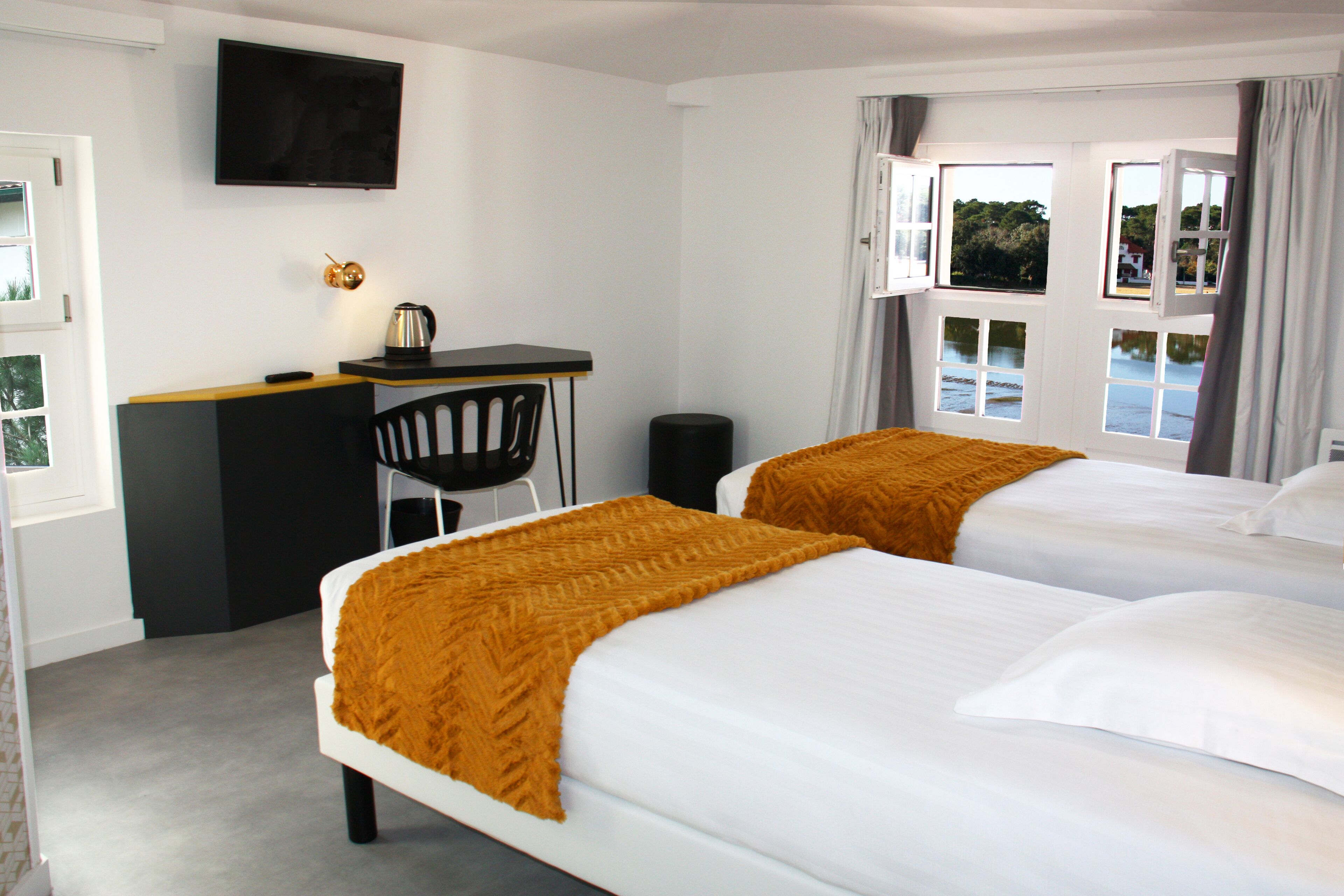 Habitación de hotel con dos camas, un escritorio, una silla y un televisor en la pared.