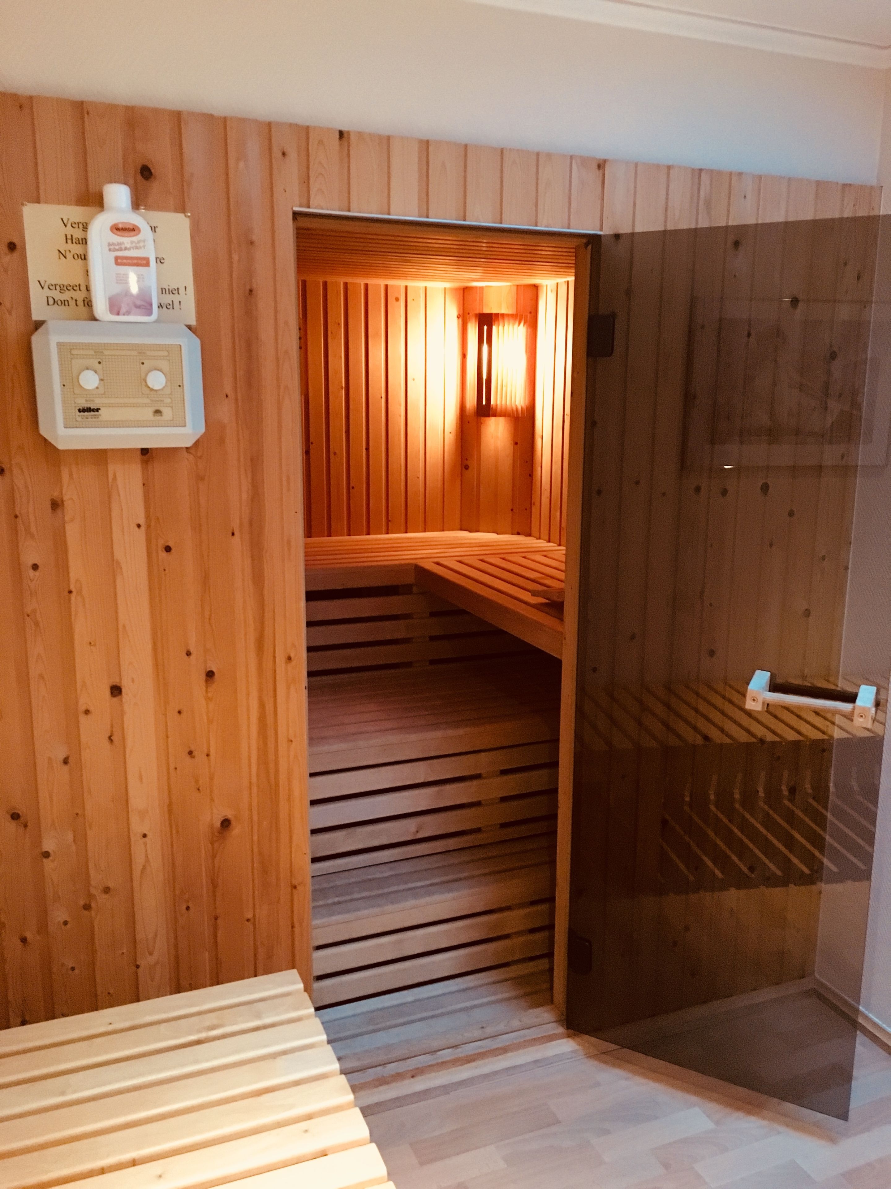 Un sauna de madera con bancos y una puerta de cristal.