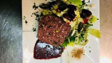 A plate with a meatloaf, salad, and a dark sauce.