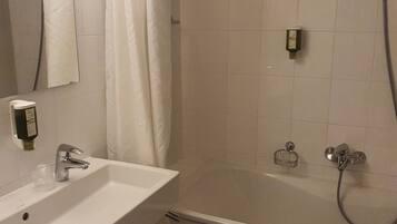 Un baño con lavamanos, espejo, ducha y toallero.