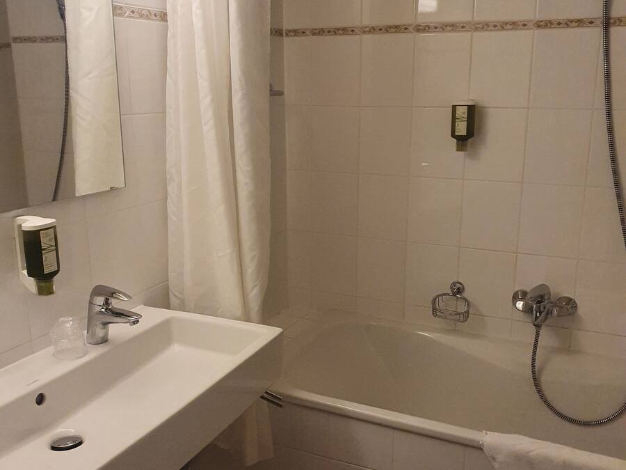 Une salle de bain équipée d’un lavabo, d’un miroir, d’une douche et d’un porte-serviettes.