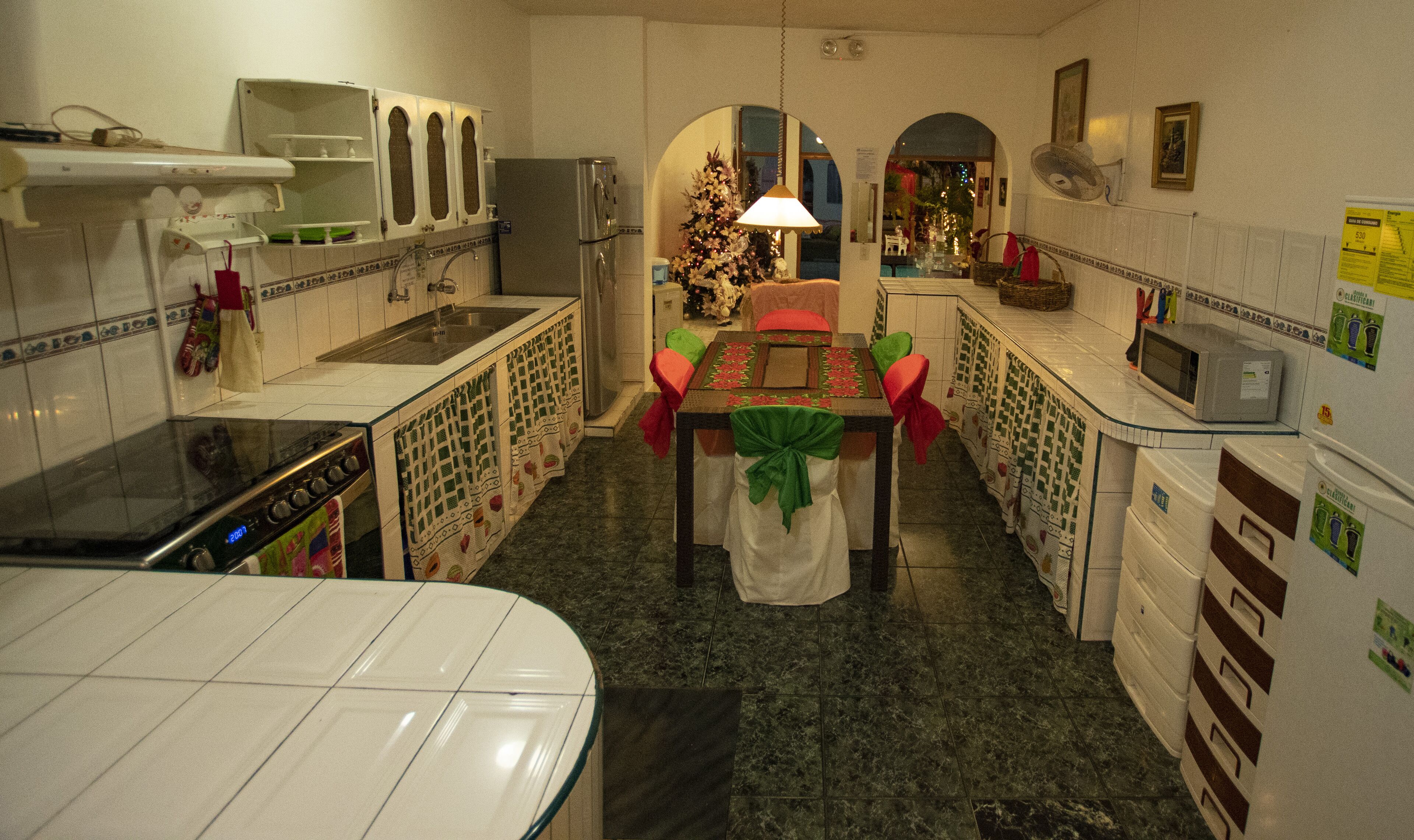 Una cucina funzionale con fornello, forno a microonde e frigorifero. Un tavolo da pranzo con sedie è sistemato al centro.