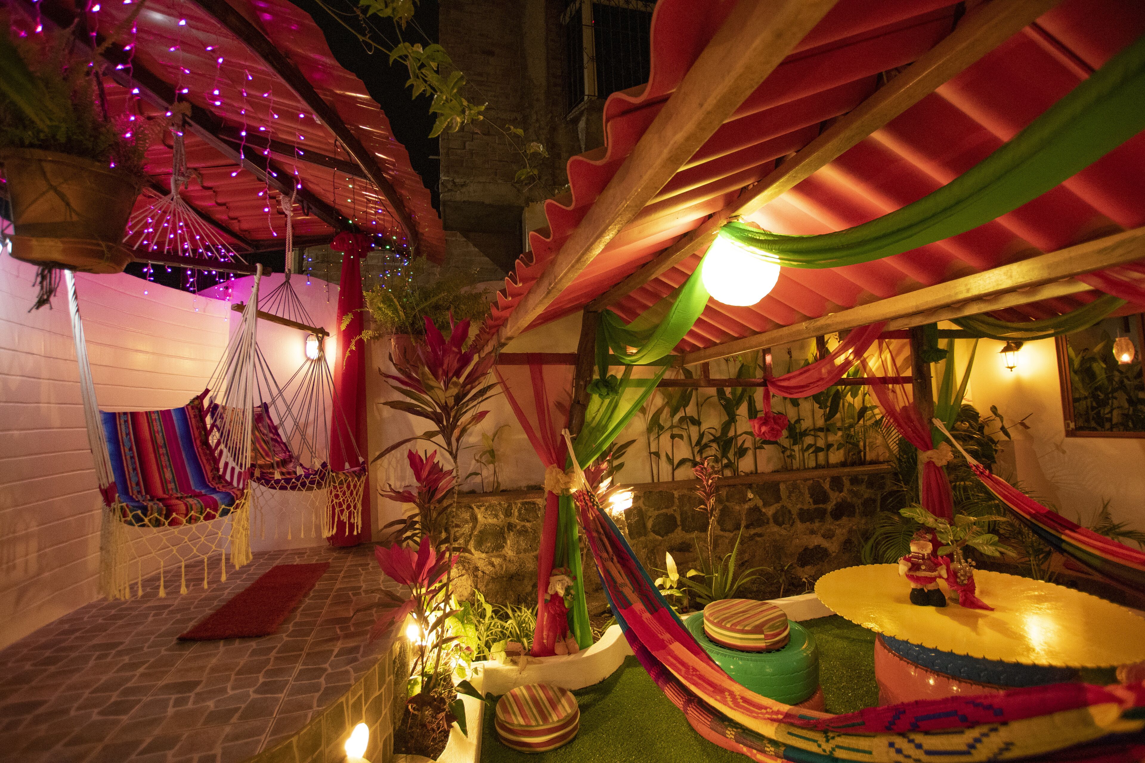 A cozy outdoor seating area with hammocks, a small stage, and decorative plants.