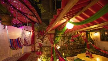 A cozy outdoor seating area with hammocks, a small stage, and decorative plants.